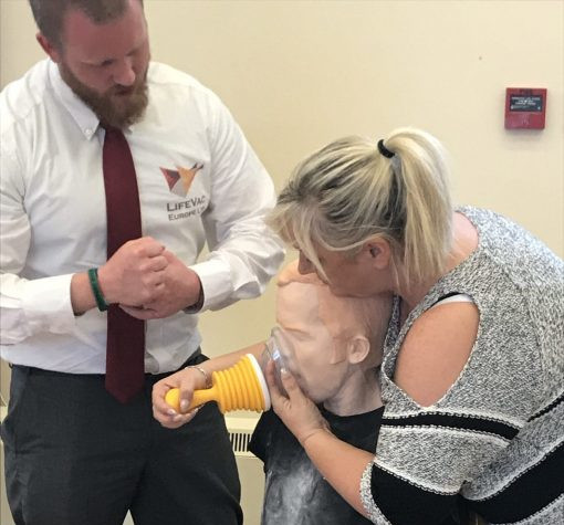 A woman practicing using a LifeVac anti choking device on a dummy