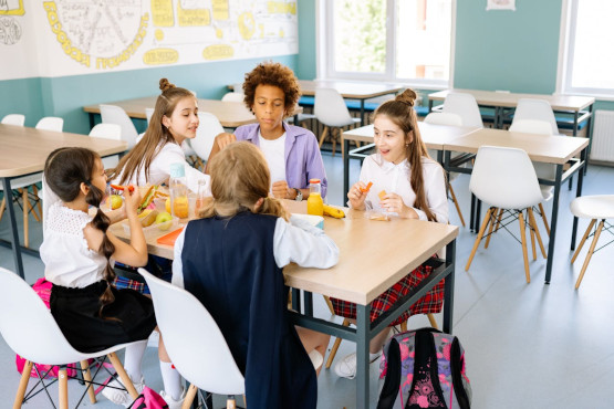 Kinder essen ihr Schulmittagessen an einem Tisch